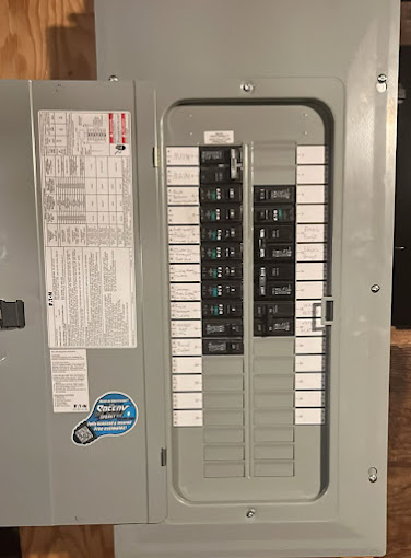 Electric circuit breaker panel with open door mounted on wooden wall