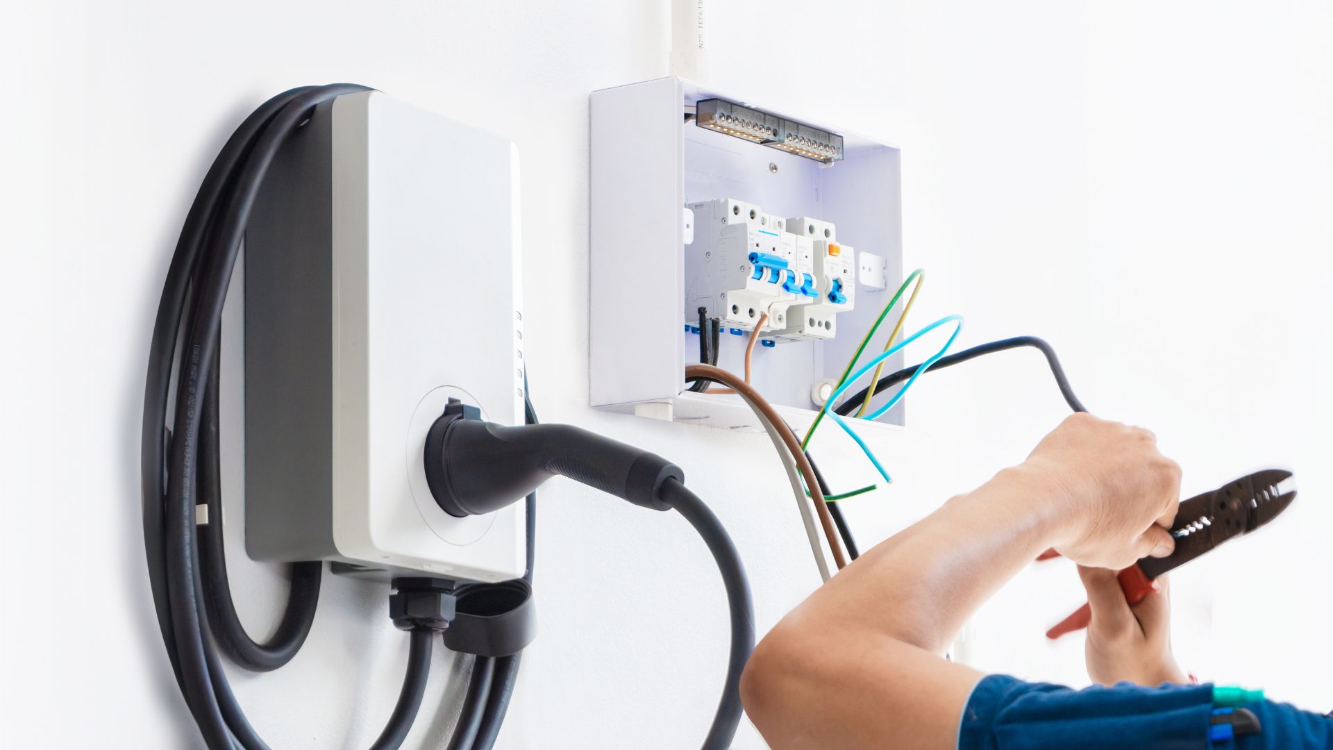 Electrical technician working on wiring and circuit breaker panel