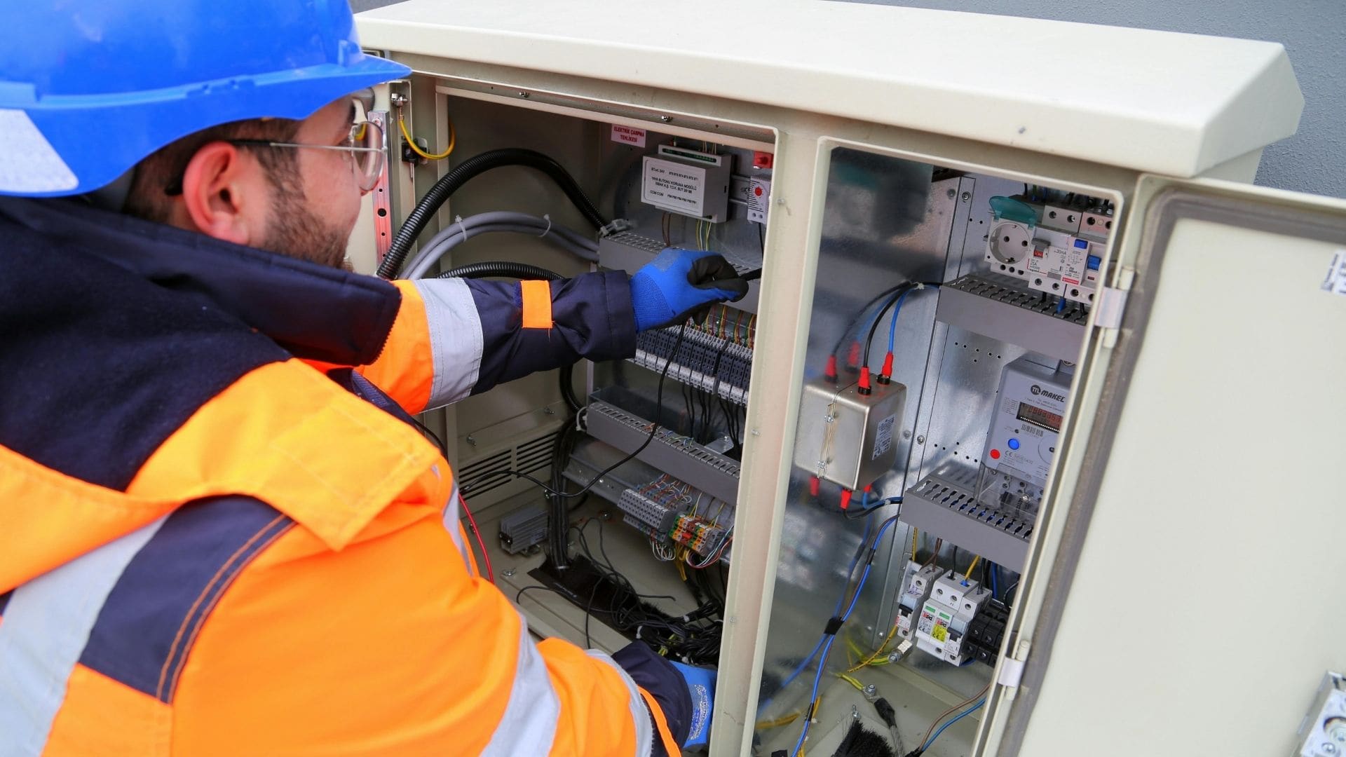 Emergency electrician in hard hat and safety vest opening an outdoor electrical enclosure