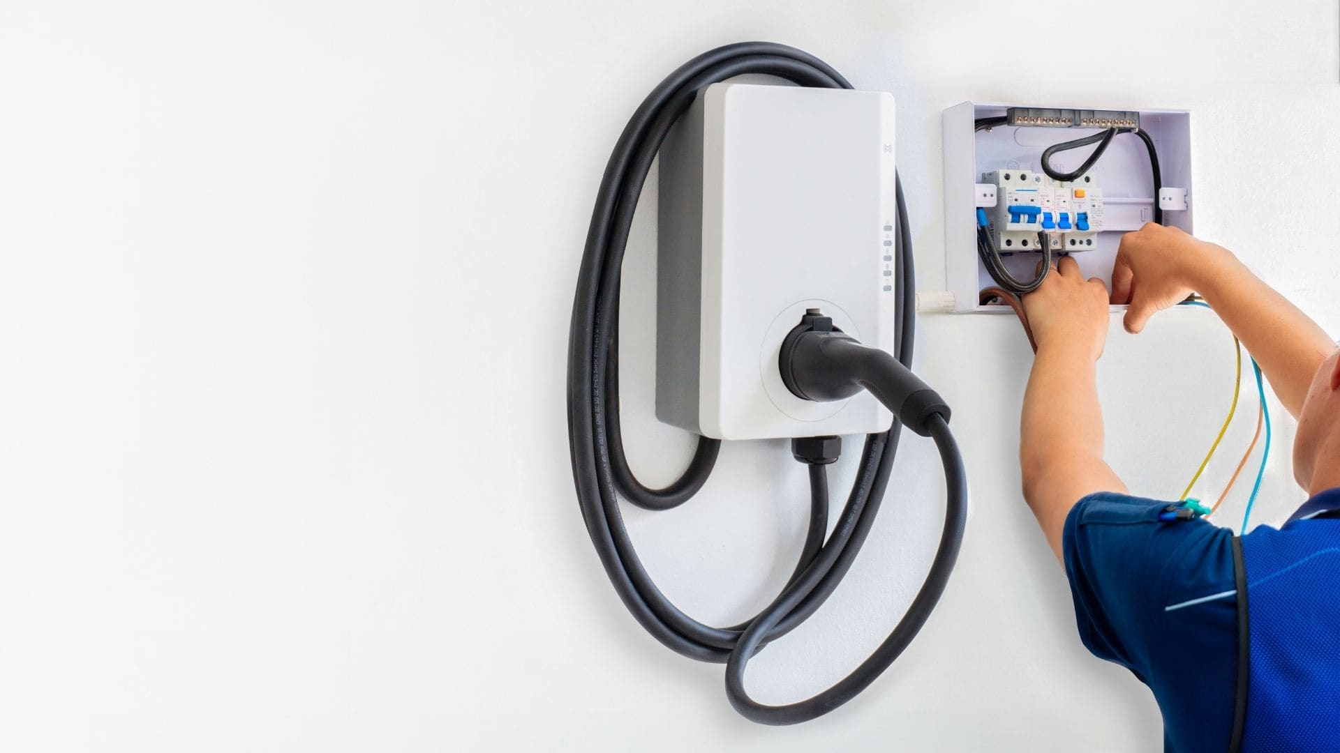 Electrician installing a wall-mounted EV charging station on a modern home