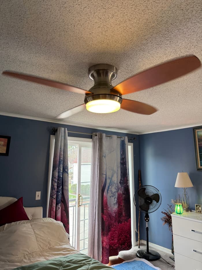 A ceiling fan with an integrated LED light installed and balanced in a bedroom.