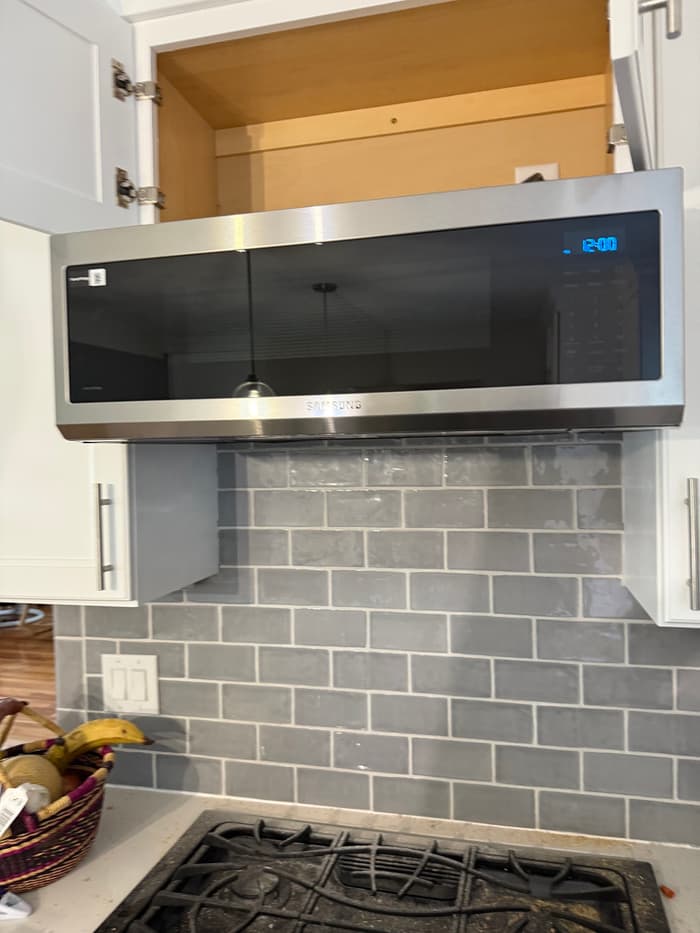 An over-the-range microwave hung and wired above a gas range during a kitchen update.