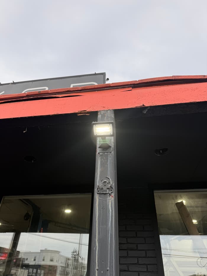 An LED wall pack lighting a storefront entry for a Manchester-area business.