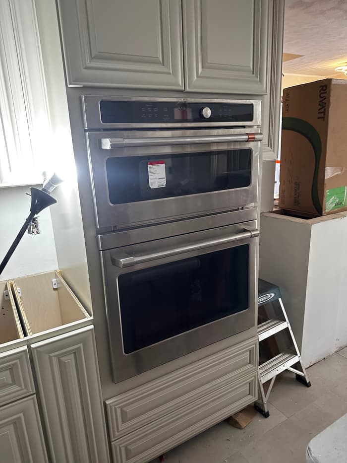 A stainless wall oven and microwave combo wired and set into the cabinet run during a kitchen remodel.