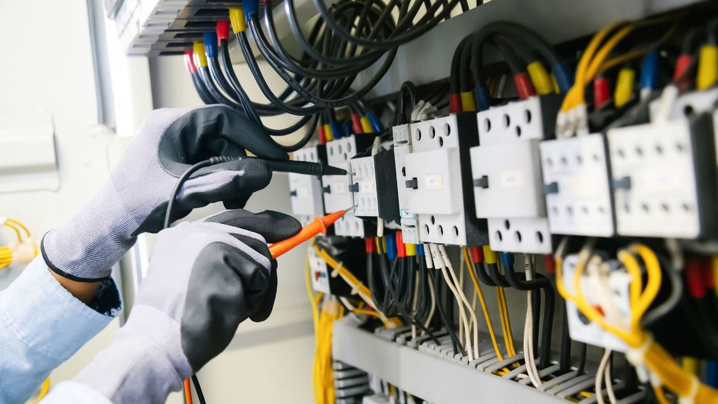 Electrician installing multiple pendant fixtures during a kitchen renovation