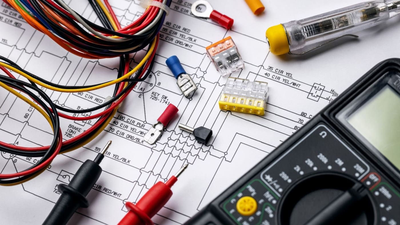 Wiring diagram, multimeter, and connectors laid out to plan an electrical repair