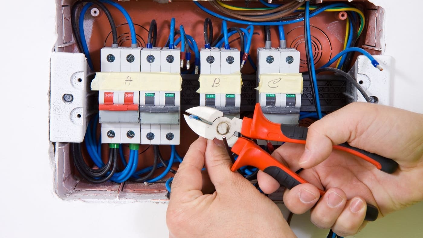 Electrician wiring circuit breakers inside an electrical panel