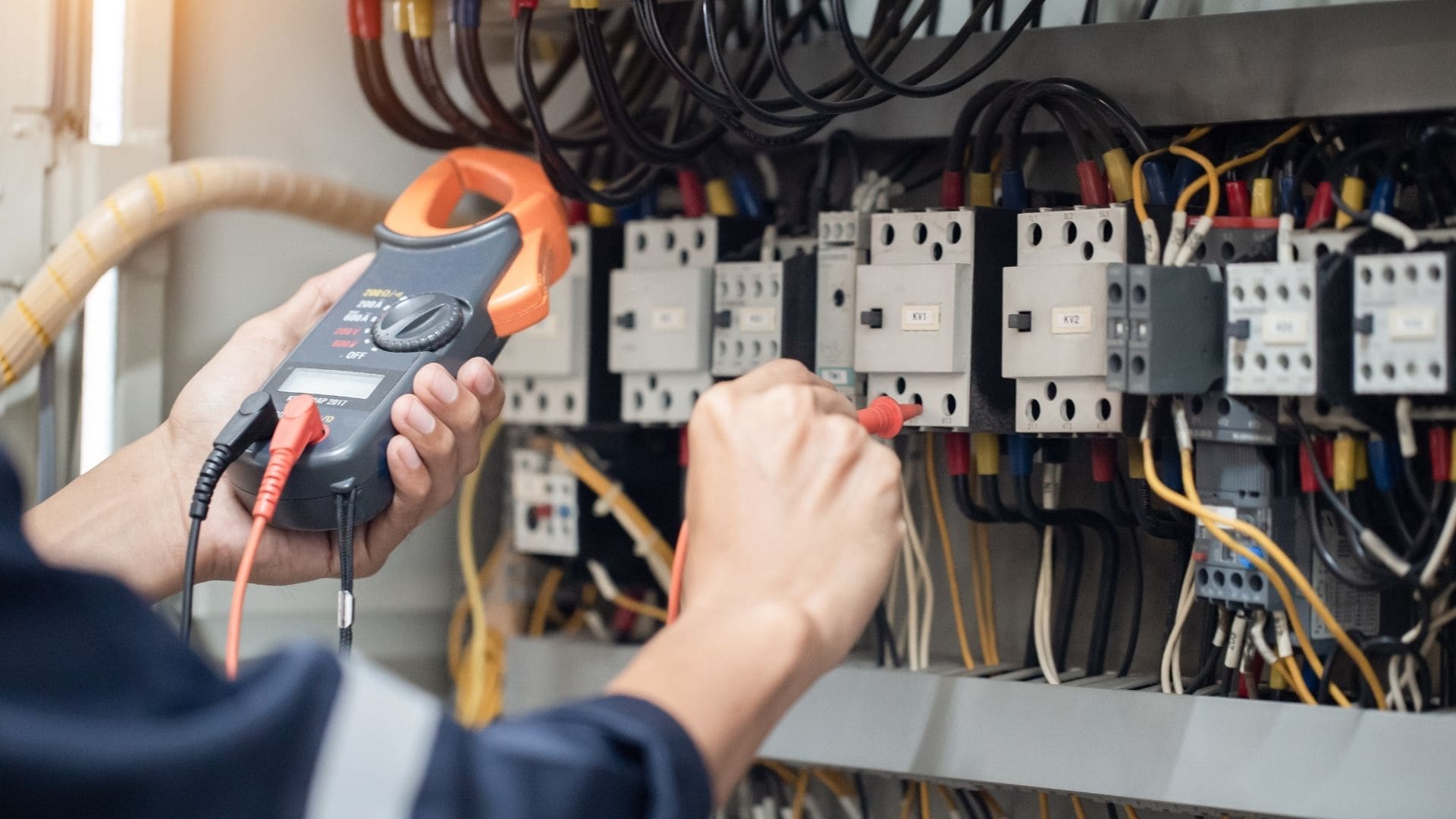 Licensed electrician testing a breaker panel with a clamp meter