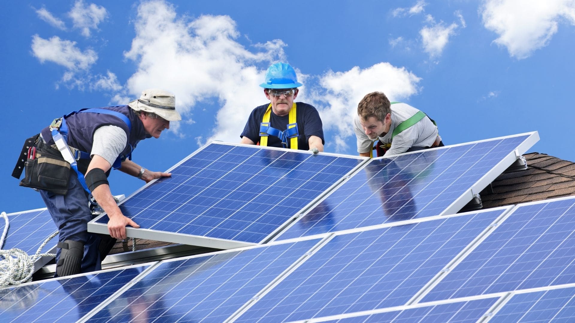 Electrical crew working on a residential roof under a bright blue sky
