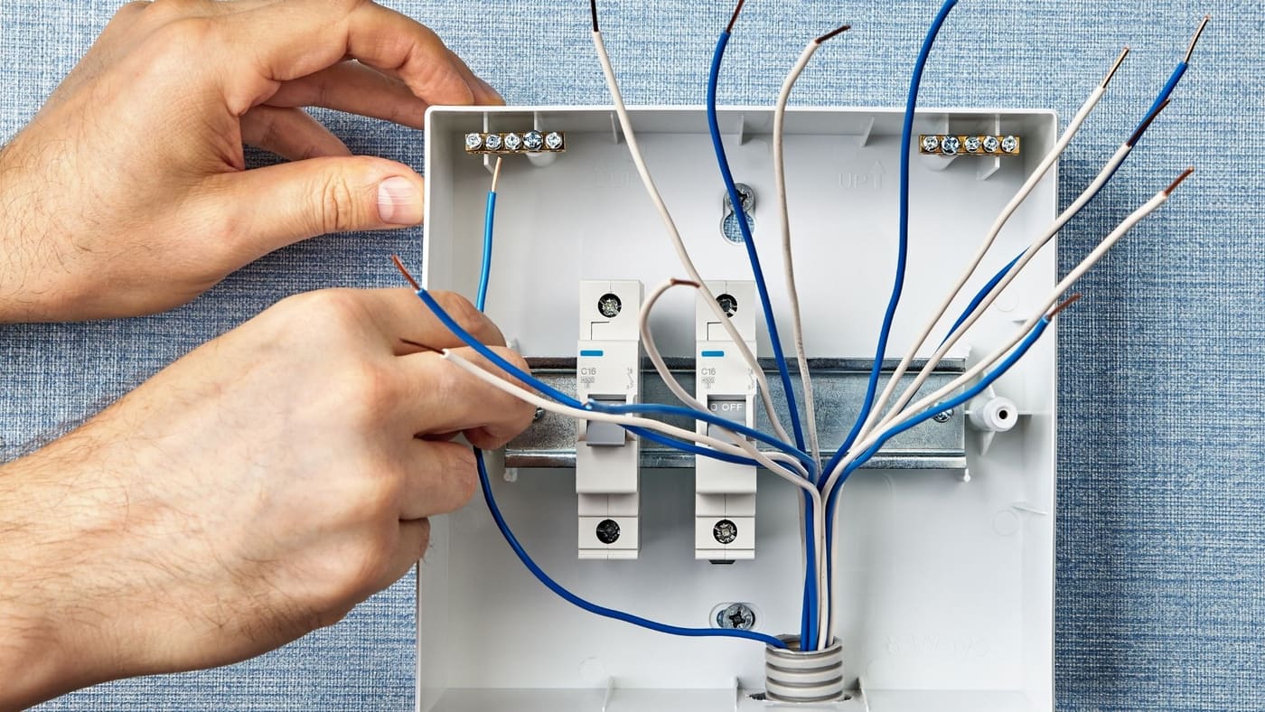Technician wiring rooftop HVAC equipment on a commercial building
