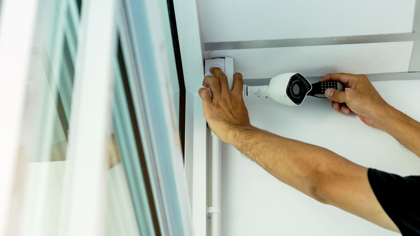 Technicians installing a security camera on an interior wall