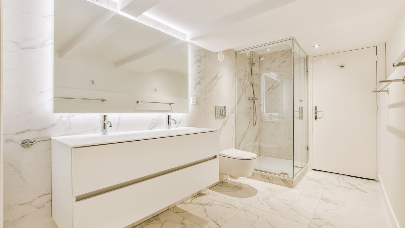 Finished bathroom remodel with marble tile and glass shower enclosure